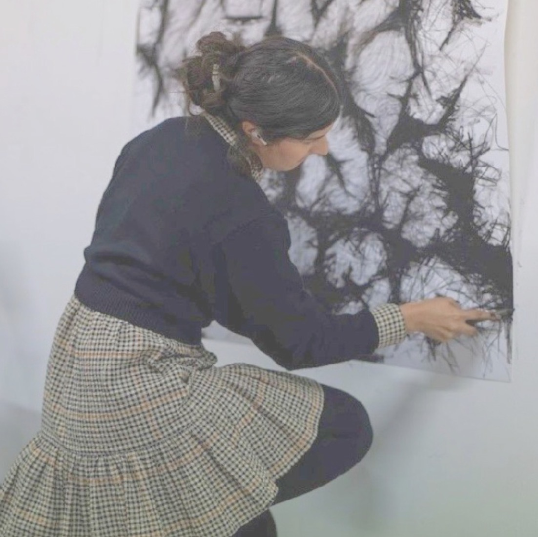 Anya Kalsi drawing into a large charcoal work on paper in the studio